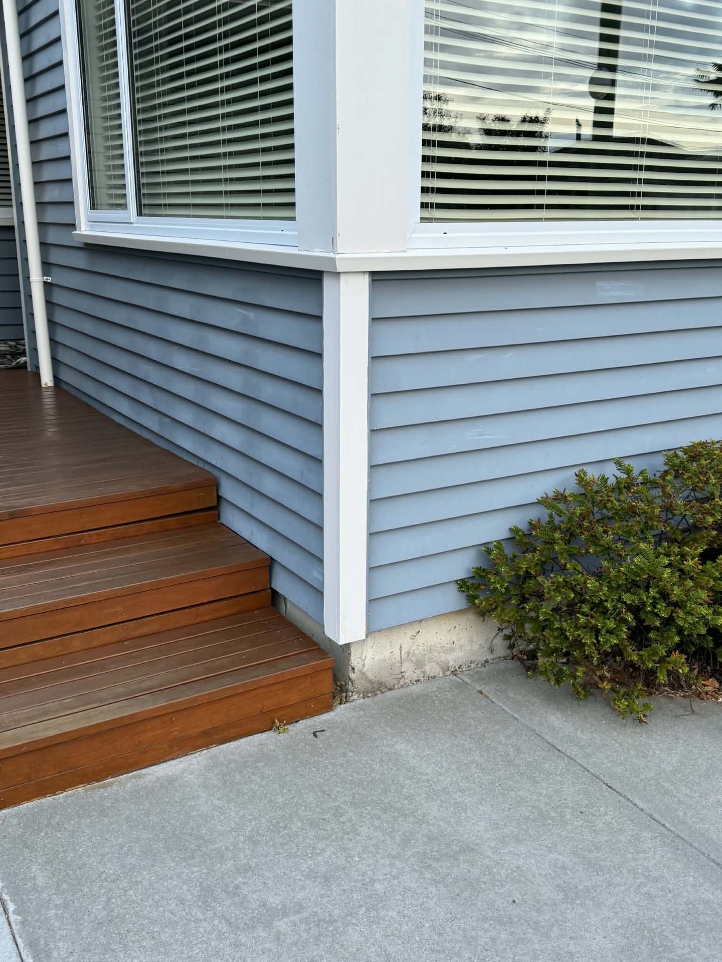 Freshly painted grey weatherboard corner with timber entry steps